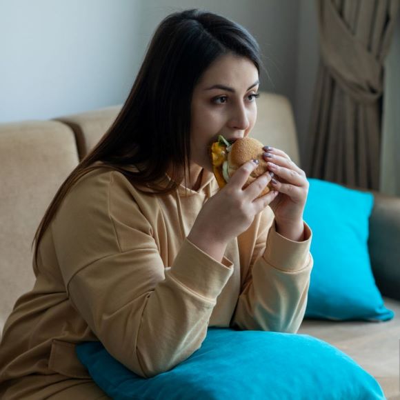 Woman on couch eating a sandwich