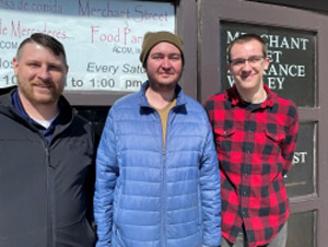 (From left to right) Chris Gibson, Michael Dusenbury and Gabrel Estby in front of food pantry entrance.