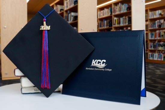 Graduation cap with "2024" tassel next to a KCC diploma holder