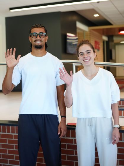 Two students waving hello