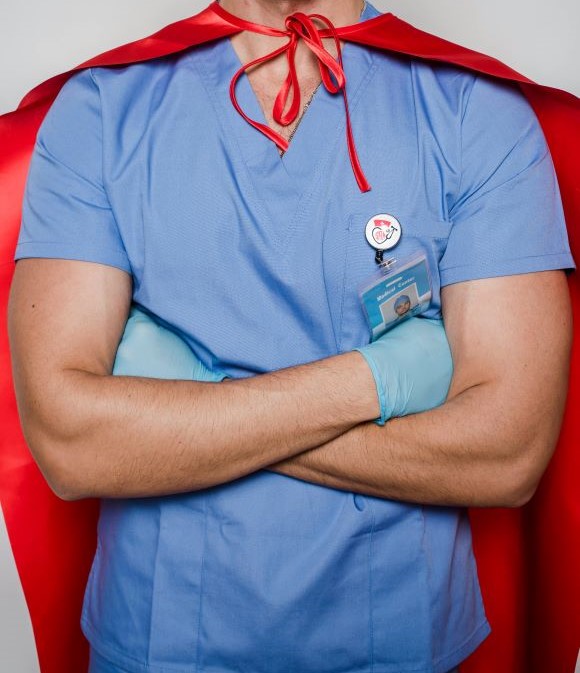 A healthcare worker wearing scrubs and a superhero cape