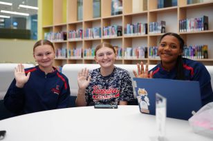 Three female students waving